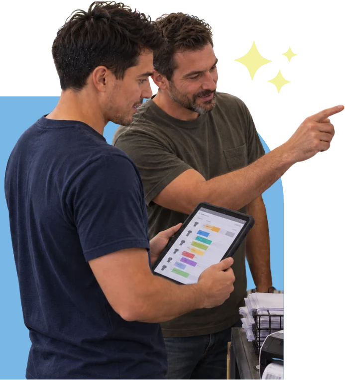 A PrintOps team member and a print shop owner going through the shop’s schedule together on a tablet, on the shop floor.